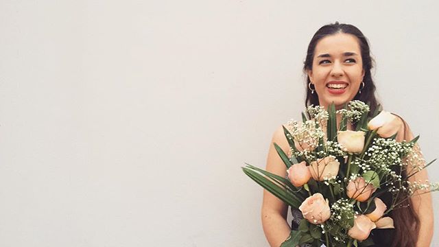 young woman smiling holding a large bouquet of pink roses