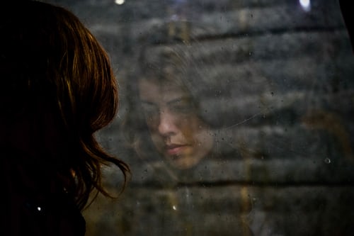 faint reflection of a woman's face in the window with a brick wall outside the window