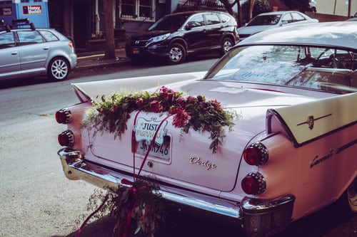 pink dodge vintage car with 'just married' sign and flowers on back