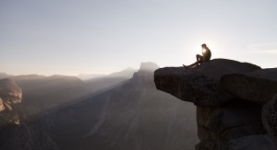 person sitting on mountain top at sunset