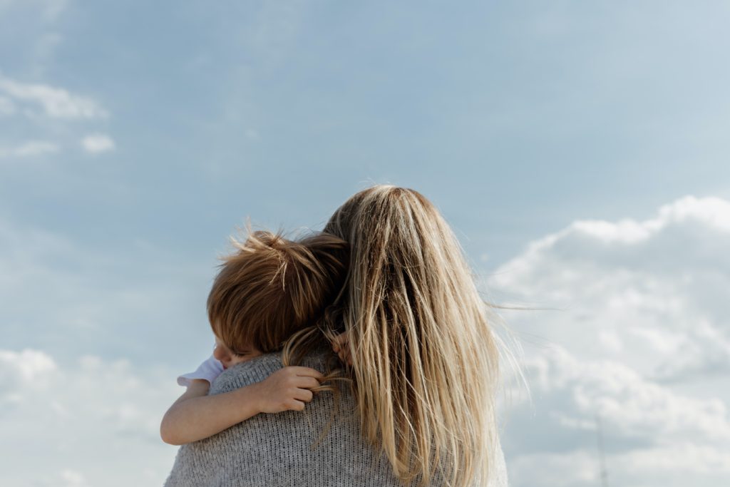 mother holding child looking at the blue cloudy sky