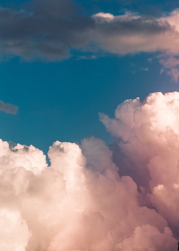 deep blue sky framed by fluffy white and pink clouds